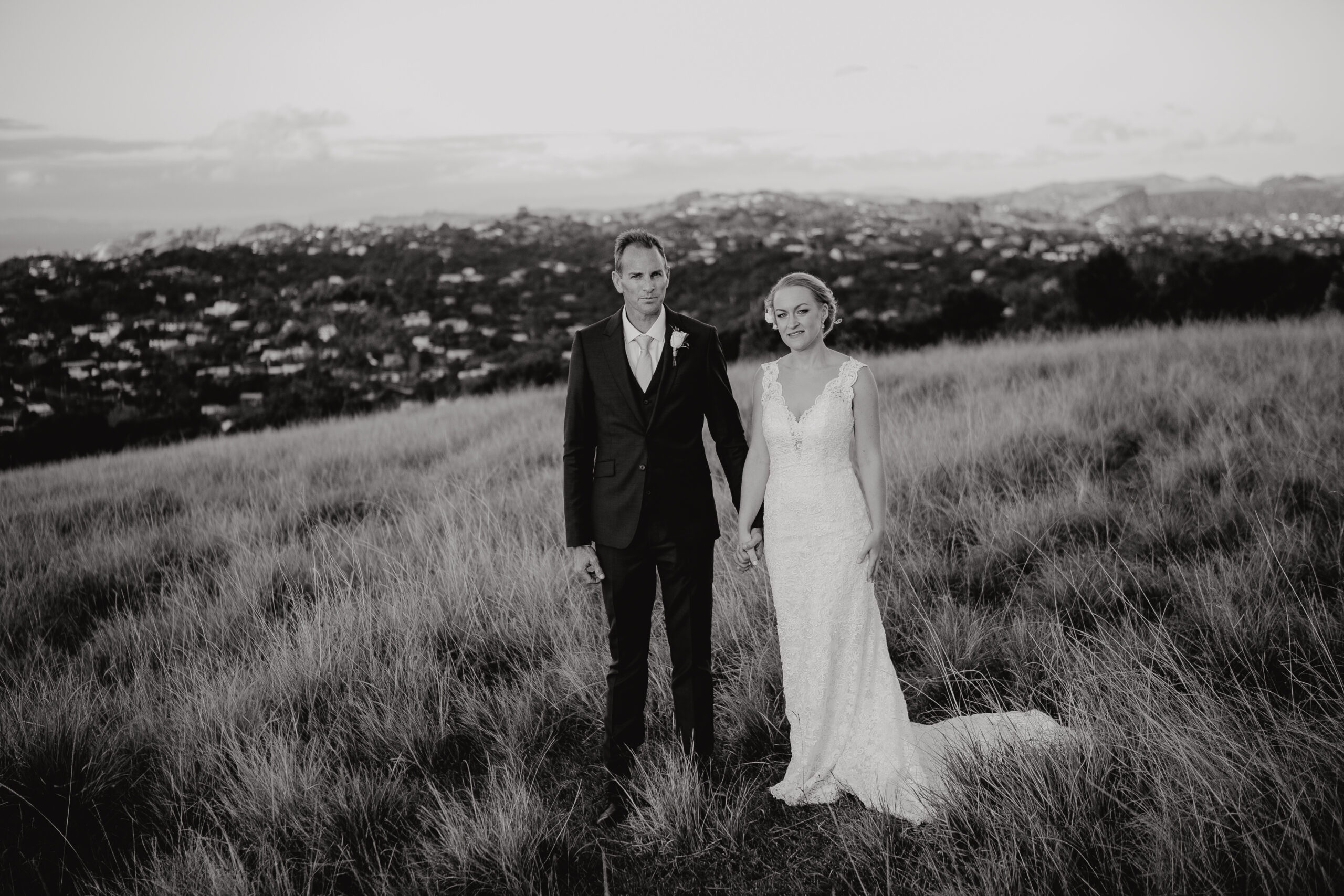 Bride and Groom wedding photos ontop hill in long grass at Mudbrick Waiheke Island Auckland, photo by Sarah Weber Photography