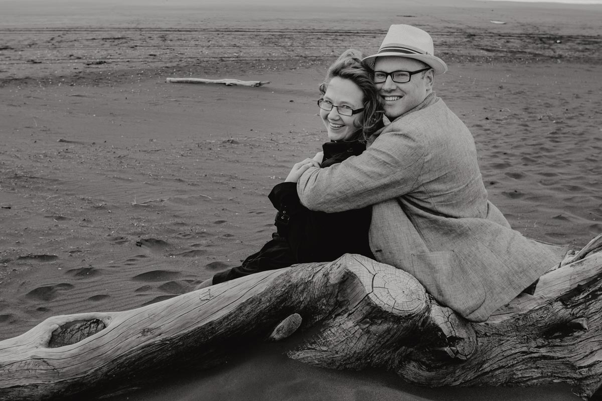 Couple portrait photo cuddling at muriwai beach in auckland by sarah weber photography