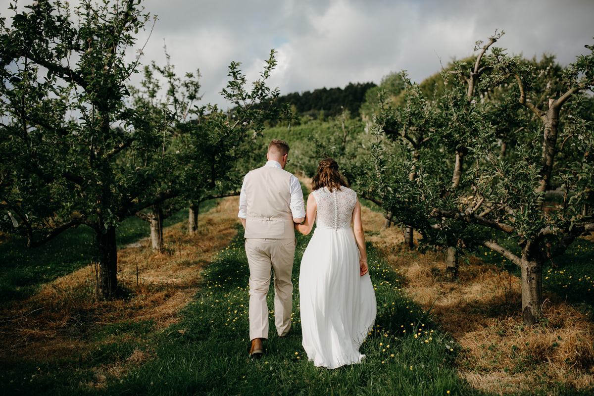 Auckland bride and groom walking in Windmill Orchards from coatesville settlers hall wedding
