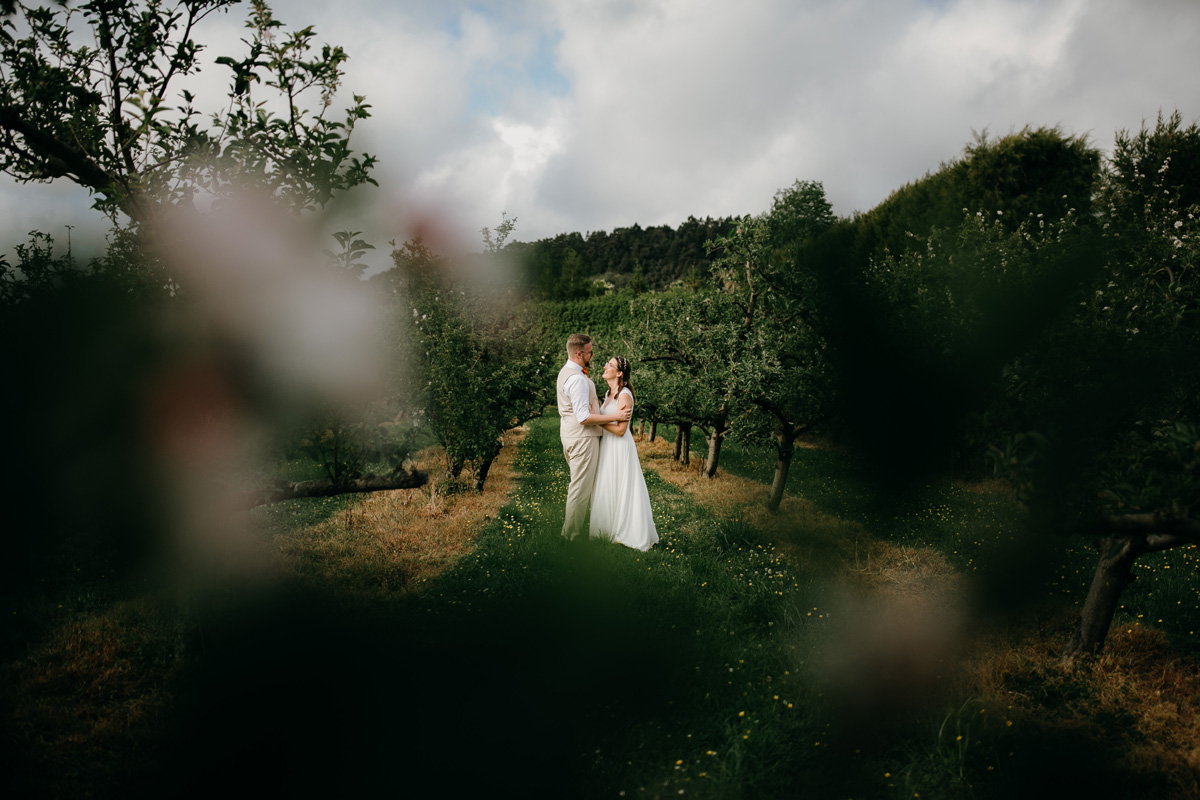 Auckland bride and groom huging in Windmill Orchards from coatesville settlers hall wedding