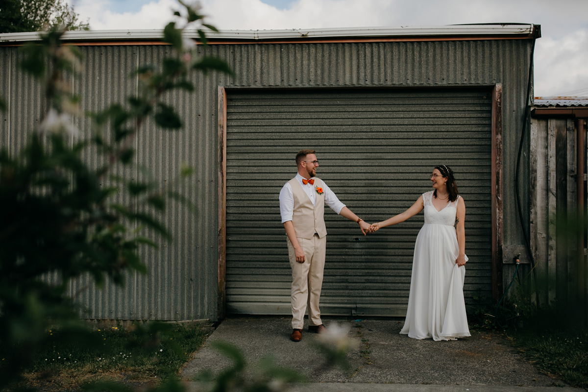 coatesville settlers hall wedding auckland bride and groom stnading outside shed Windmill Orchards