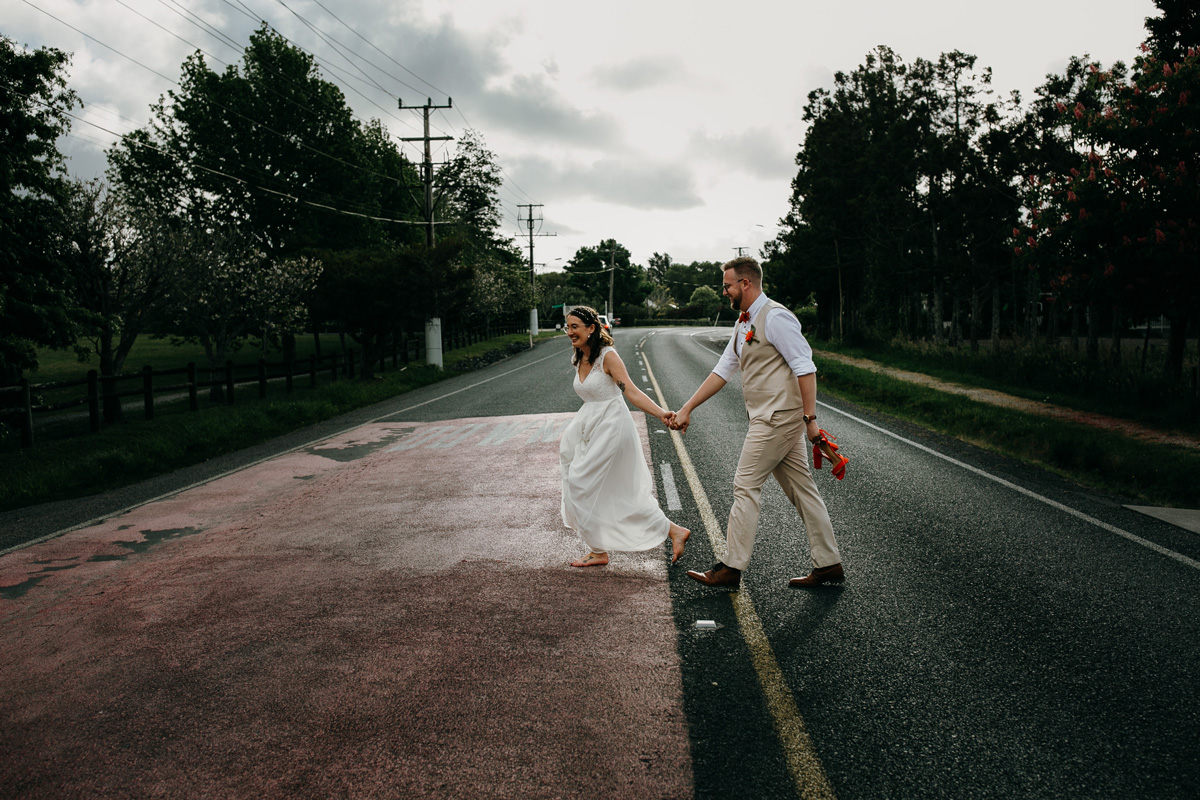 coatesville settlers hall wedding auckland bride and groom running on road photos by sarah weber photography