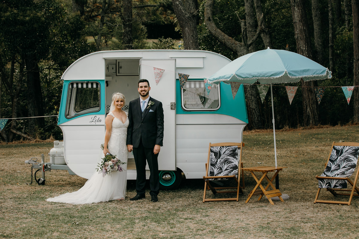 Bride and Groom posing infront of Caravan at The Brigham Restaurant & Cafe in Whenuapai, Auckland photo by Sarah Weber Photography