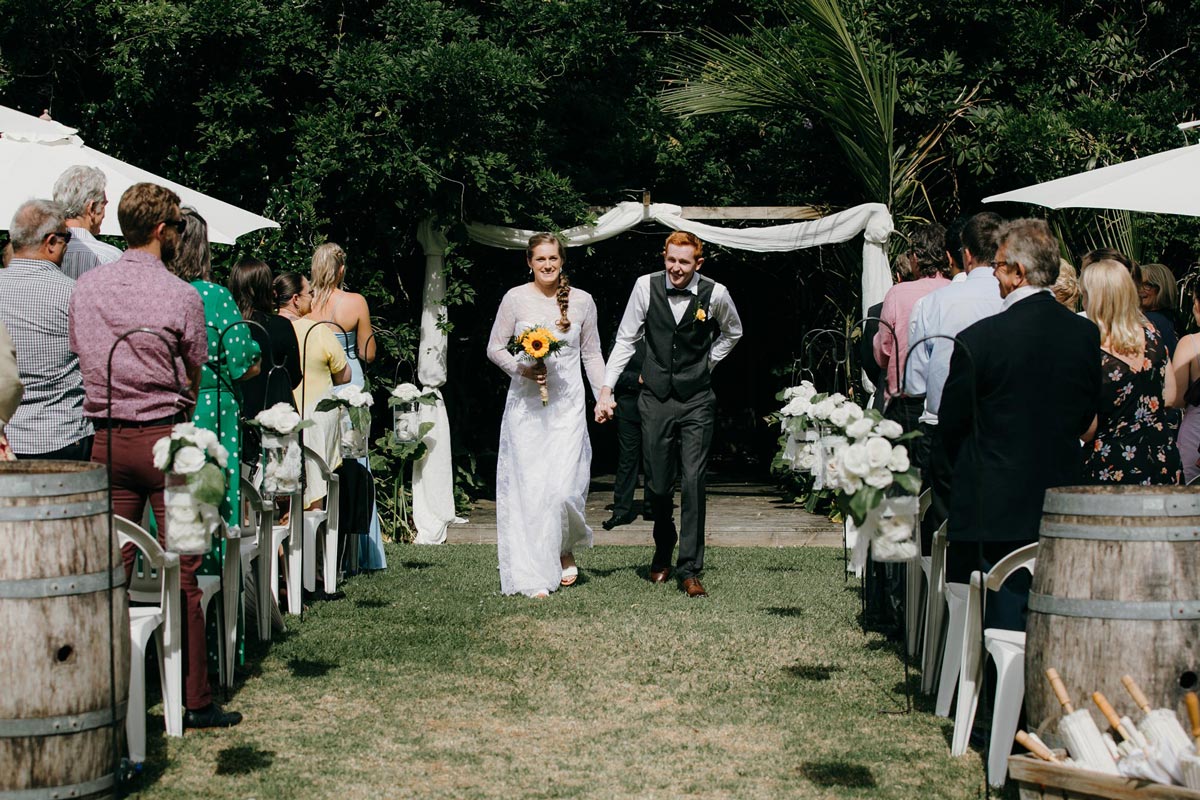 bride and groom walking down aisle at bridgewater country estate venue in Kaukapakapa, Auckland photo by sarah weber photography