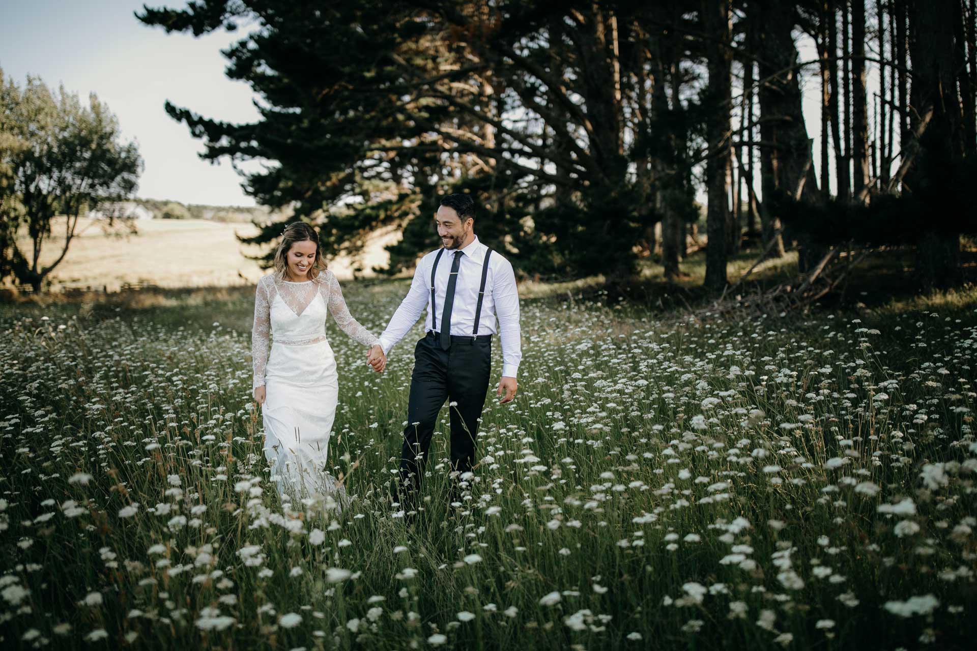 bride and groom walking in long grass auckland photos by sarah weber photography