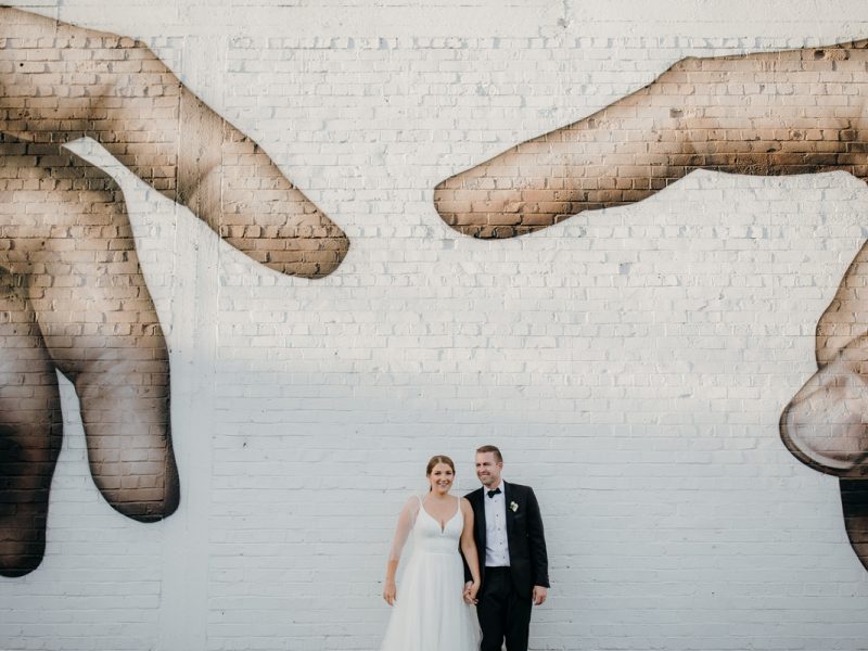 bride and groom infront of hand mural outside glasshouse morningside wedding photo by sarah weber photography